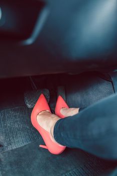 Woman driving a car in an unsafe manner with red high-heel shoes