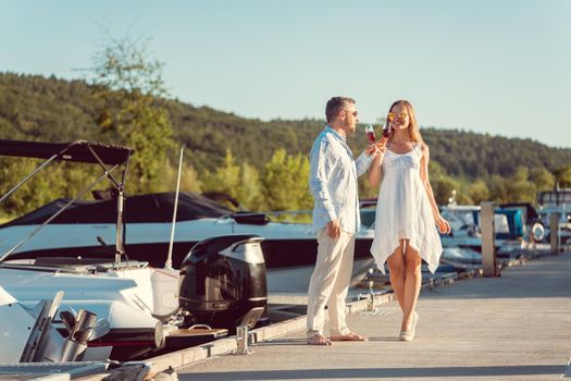 Elegant couple walking between the boats on a river port