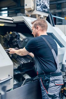 Experienced worker changing tool setup of lathe machine on the factory floor