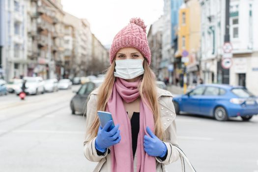 Concerned woman standing in lockdown city with medical mask looking into camera