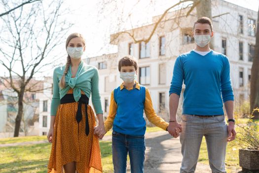 Family having a walk in the sun during corona virus emergency wearing face masks