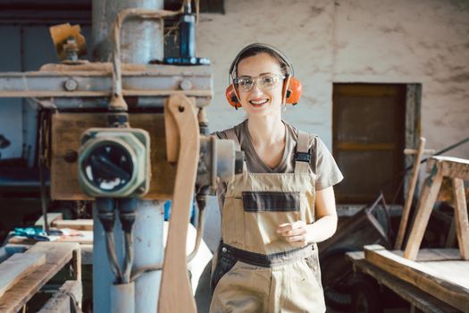 Woman carpenter in traditional carpentry adjusting the machine planer by hand