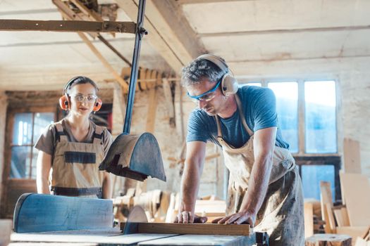 Team of carpenters working on details of a wood cut in their vintage workshop