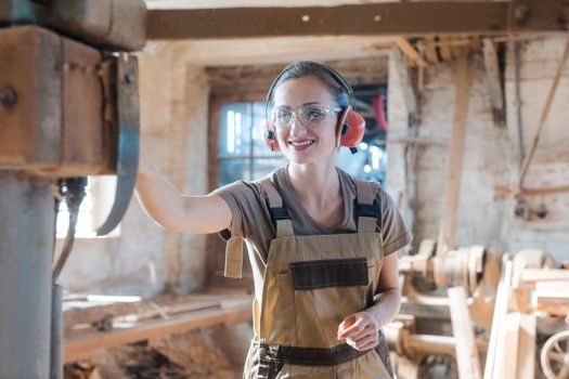 Woman carpenter in traditional carpentry adjusting the machine planer by hand