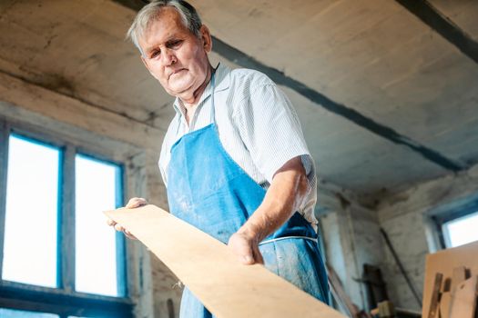 Experienced carpenter checking if a plank is plane and can be used