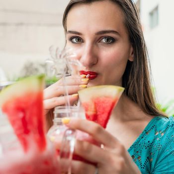 Beautiful woman drinking watermelon juice in bar or cafe handed to her by boyfriend or man