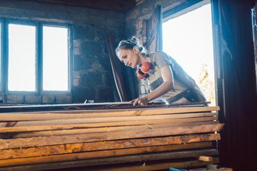Woman carpenter choosing wood in her storage for next project