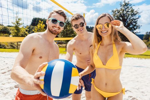 Group of people in recreation time playing beach volleyball having a good time