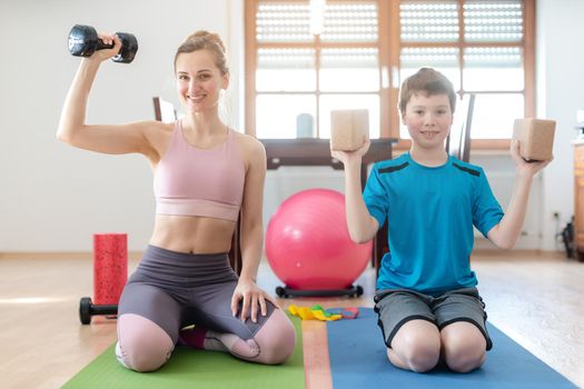 Mother and son doing weight training at home during lockdown curfew with dumbbells