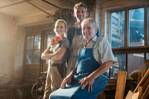 Generations of carpenters in their family business workshop looking at the camera