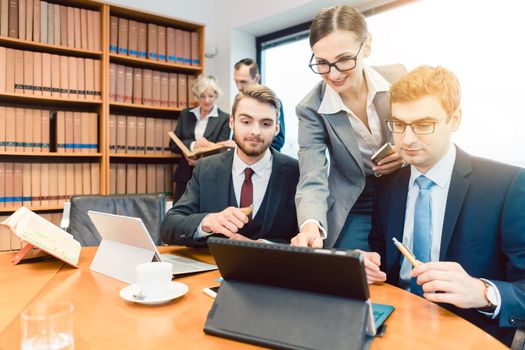 Young but diligent Lawyers in their law firm working on computer with books in background