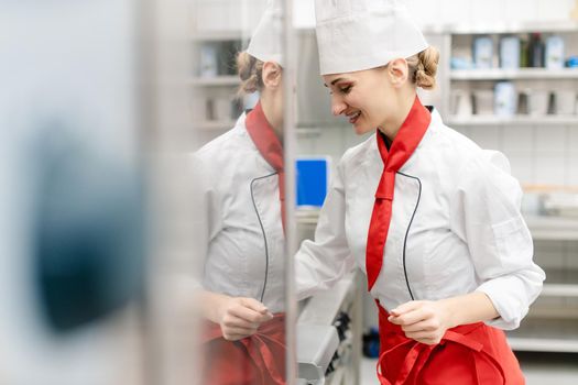 Cook in large commercial kitchen stirring sauce looking at camera