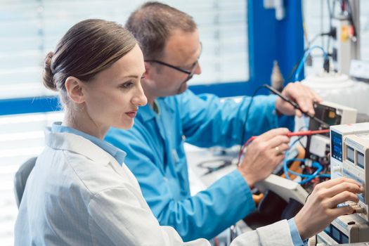 Two electronic engineers on the lab test bench measuring a new product for EMC compliance