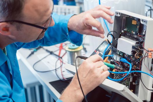 Electronics engineer man troubleshooting defects in a hardware product on his test bench