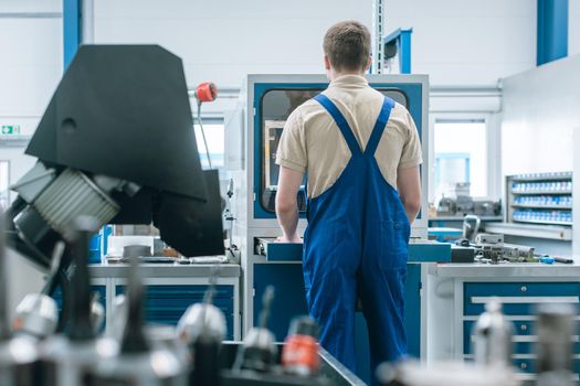 Man working in factory on semi automatized industrial production line of the metal industry