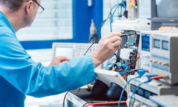 Electronics engineer man troubleshooting defects in a hardware product on his test bench