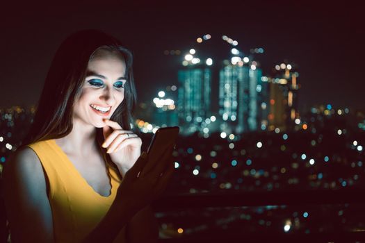 Woman checking her phone in front of big city skyline