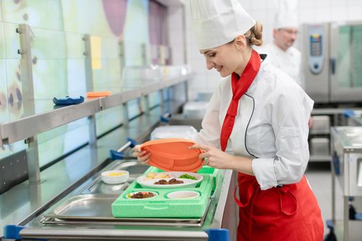 Chef in commercial kitchen preparing meal in heat retaining packaging for delivery