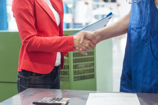 Worker in the metal industry and manager doing handshake on factory floor