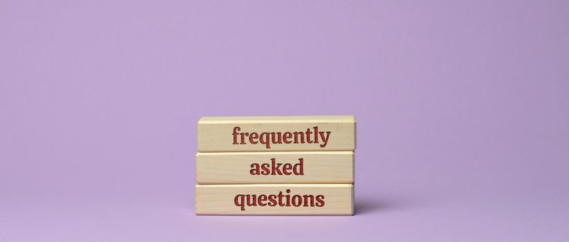 inscription frequently asked questions on wooden blocks on a purple background. QA concept, help and tips