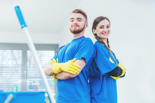 Cleaners being proud of their service standing arms folded, team of woman and man