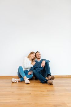 Couple dreaming about their future in the new apartment sitting on the floor