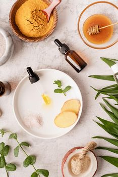 Natural cosmetics ingredients for skincare, body and hair care. Top view bottles with facial treatment product, tropical leaves