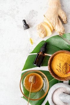 Natural cosmetics ingredients for skincare, body and hair care. Top view bottles with facial treatment product, tropical leaves