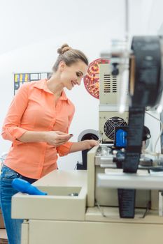 Worker woman checking textile label fresh from the printing machine