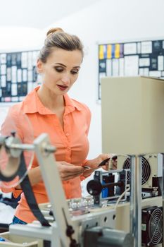 Worker woman checking textile label fresh from the printing machine