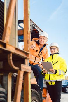 Supervisor woman instructing forklift driver what to work on next