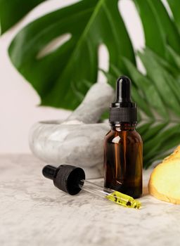 Natural cosmetics ingredients for skincare, body and hair care. Front view bottle with facial treatment product, tropical leaves