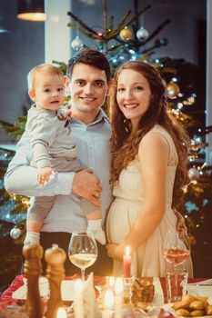 Happy family with toddler and pregnant wife celebrating Christmas