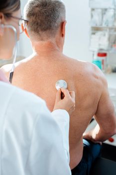 Doctor using stethoscope to check lung function on back of man