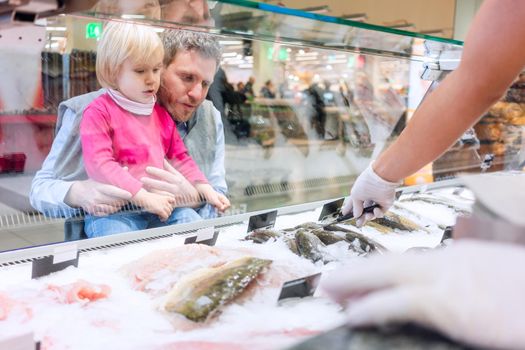 Family buying fish in the supermarket standing in front of the counter