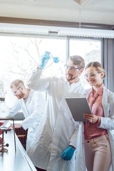 Team of scientists during experiment in the lab looking at test glass