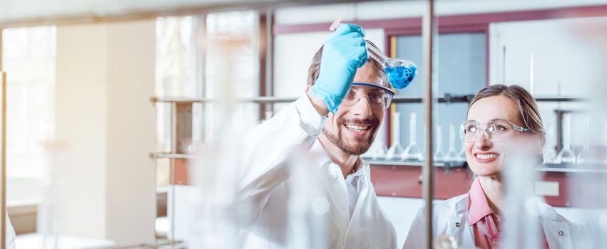 Team of scientists during experiment in the lab looking at test glass