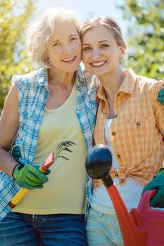 Woman gardening together in summer looking at each other