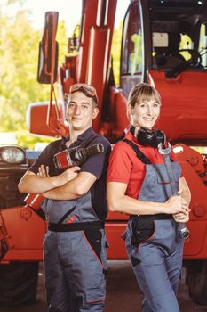 Two machinists for farm machinery in their garage standing shoulder to shoulder