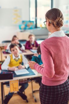 Teacher with her students in class at elementary school giving them an education