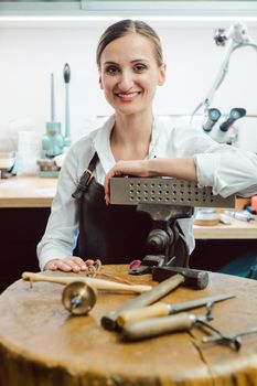 Jewelry designer in her workshop boating with her tools looking at the camera