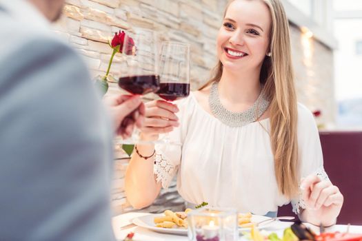 Couple toasting with red wine in romantic restaurant looking at each other