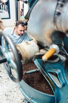 Man operating coffee roaster in his factory