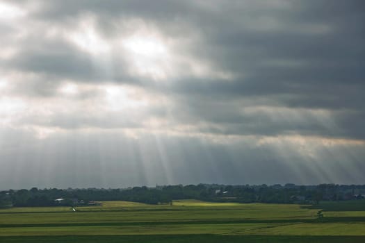 Beautiful countryside and sunrays passing through clouds on landscape with fields near Kiel - Schleswig-Holstein - Germany.