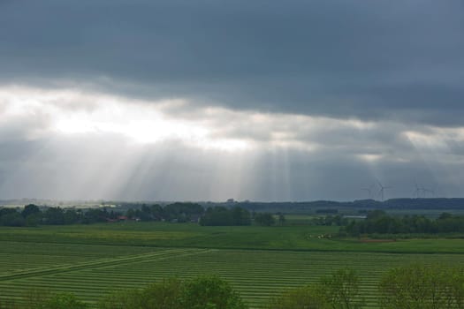 Beautiful countryside and sunrays passing through clouds on landscape with fields near Kiel - Schleswig-Holstein - Germany.