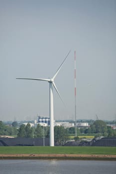 Windmills power plant and turbines generating renewable green energy near to Kiel canal in Germany.