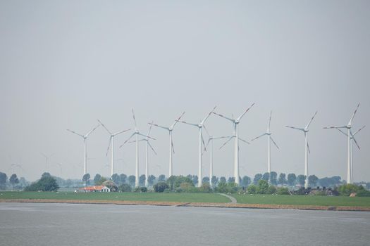 Windmills power plant and turbines generating renewable green energy near to Kiel canal in Germany.