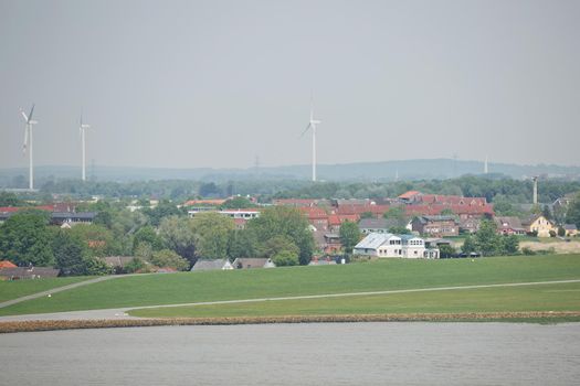 Windmills power plant and turbines generating renewable green energy near to Kiel canal in Germany.