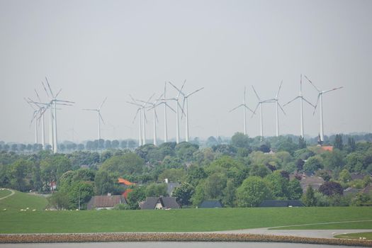 Windmills power plant and turbines generating renewable green energy near to Kiel canal in Germany.