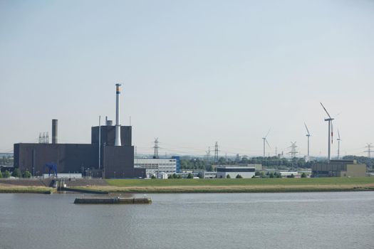 Windmills power plant and turbines generating renewable green energy near to Kiel canal in Germany.